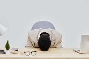 overworked,man,with,head,on,desk,in,office,workspace,,surrounded