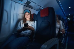 female,clicking,her,smartphone,during,night,flight